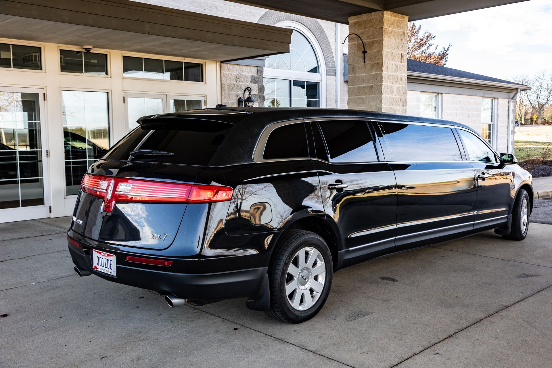 A black limousine is parked in front of a building.