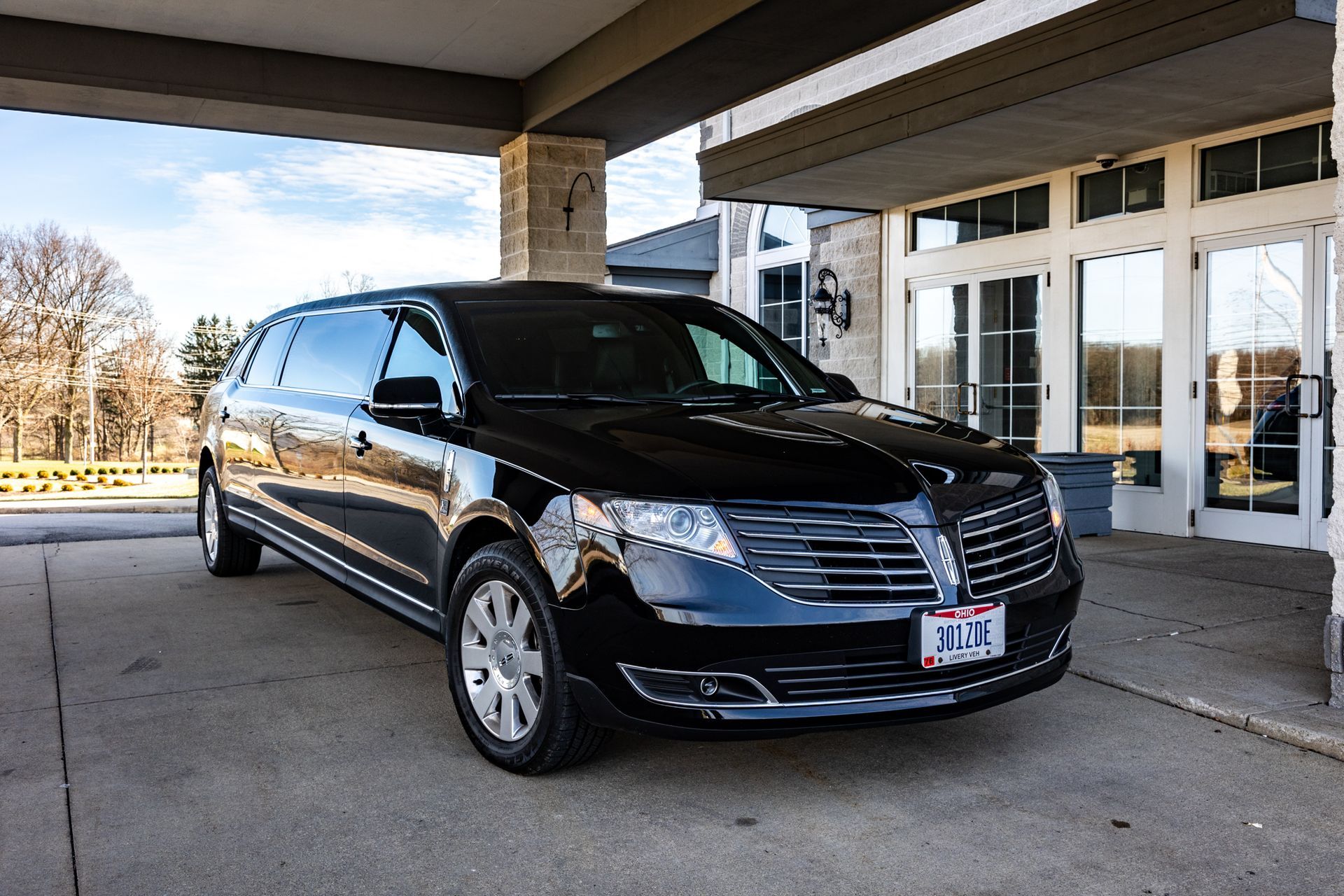 A black limousine is parked in front of a building.