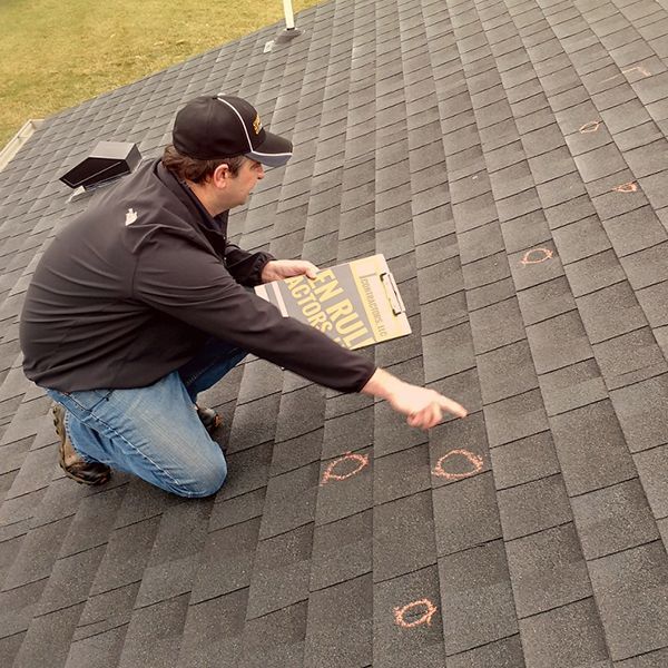 a man is kneeling on a roof looking at roof damage