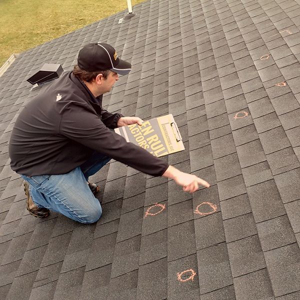 man inspecting hail damage on a roof 