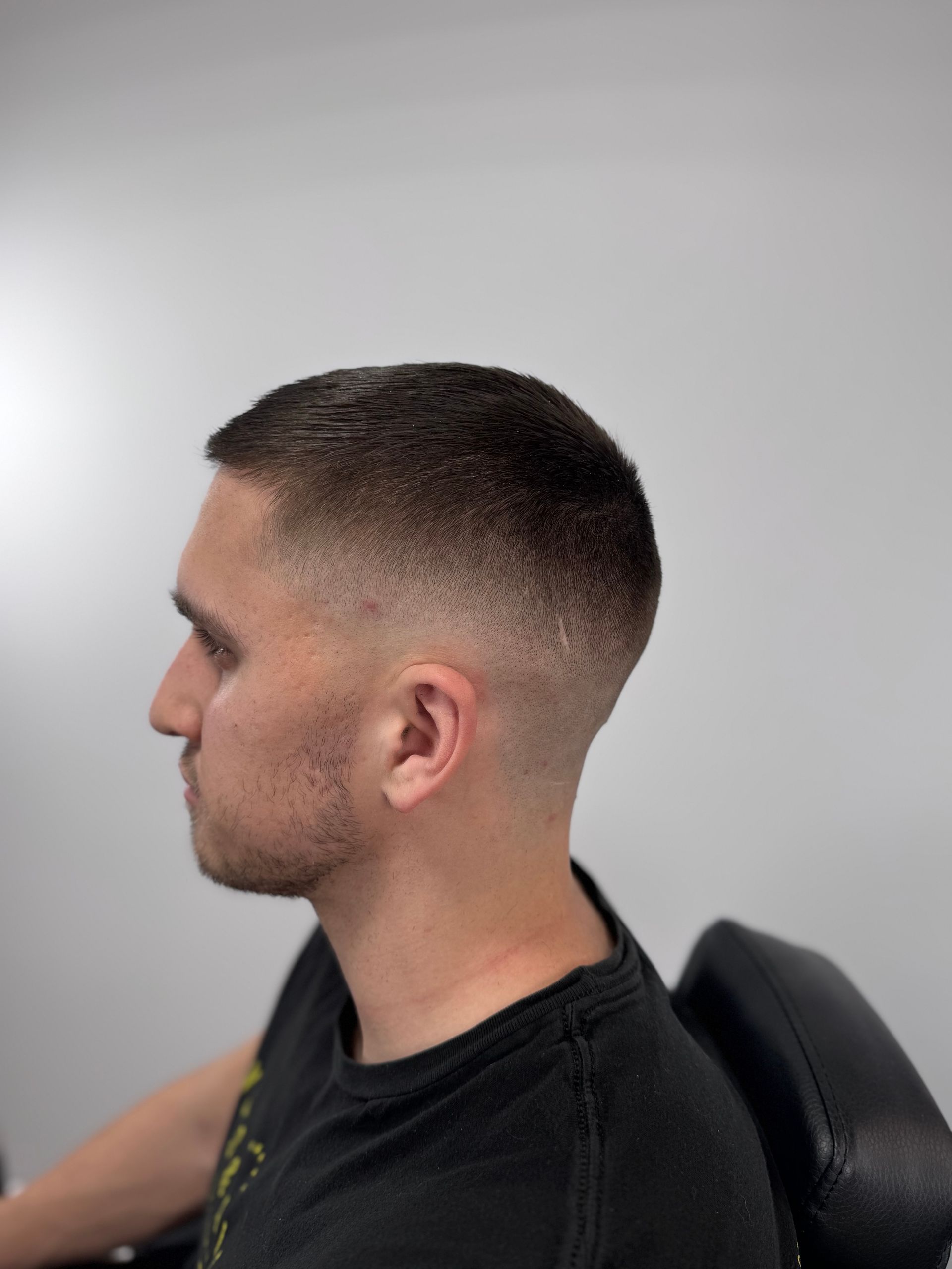 Man with a faded haircut, dark hair, and close shave on the sides and back of head.