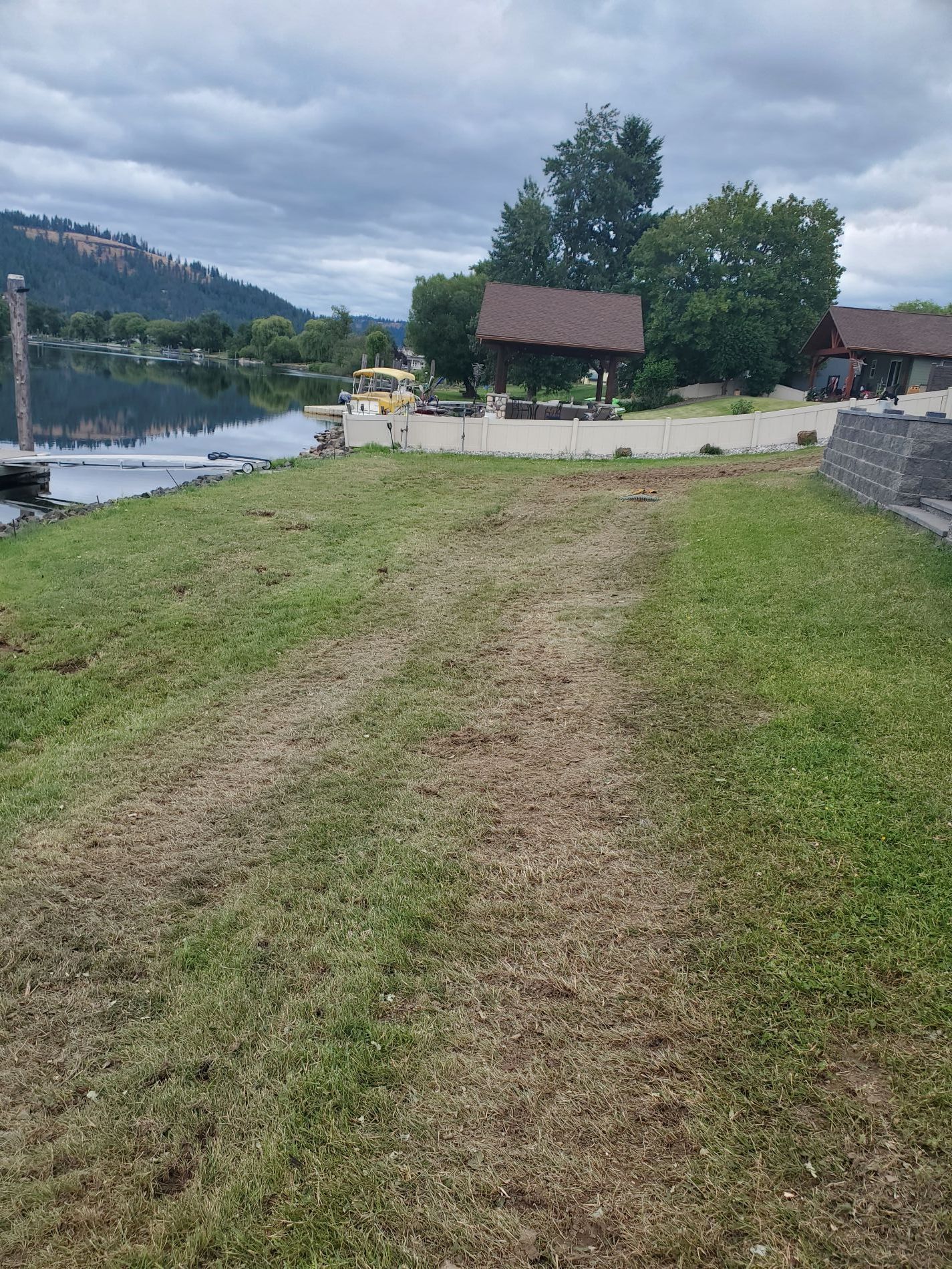 Grassy area leads to a water view with buildings and a cloudy sky.