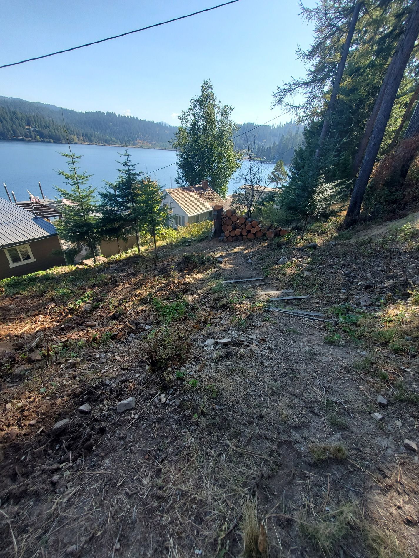 A sloped, dirt pathway with a view of a lake and houses.