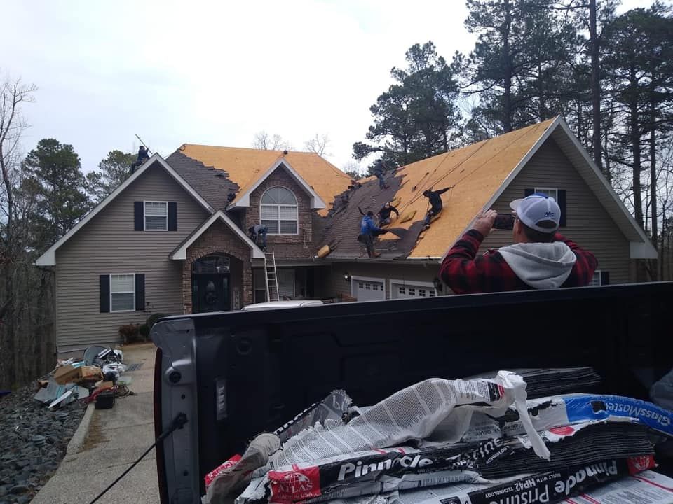 A man is sitting in the back of a truck looking at a house being remodeled