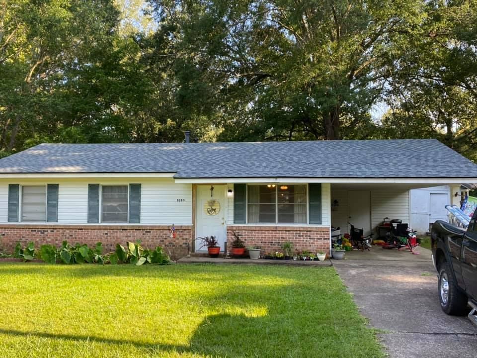 A white house with a gray roof and a truck parked in front of it.