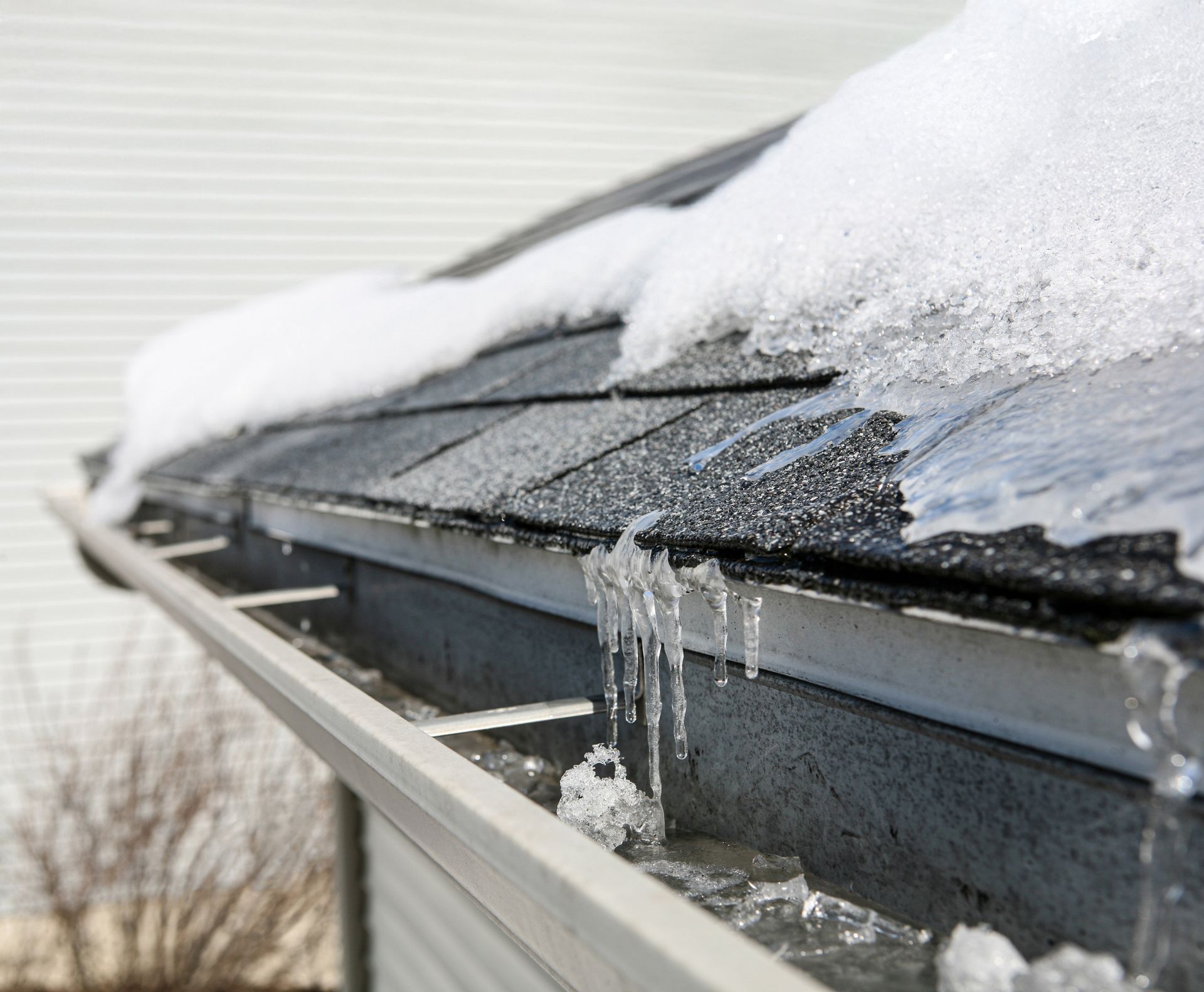 Snow and ice on a roof, melting into a gutter.