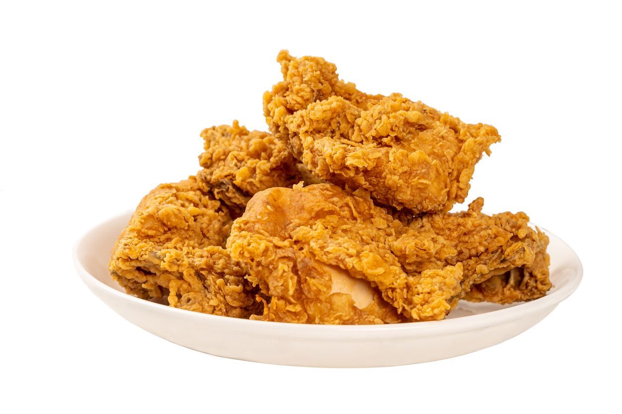 A white plate topped with fried chicken on a white background.