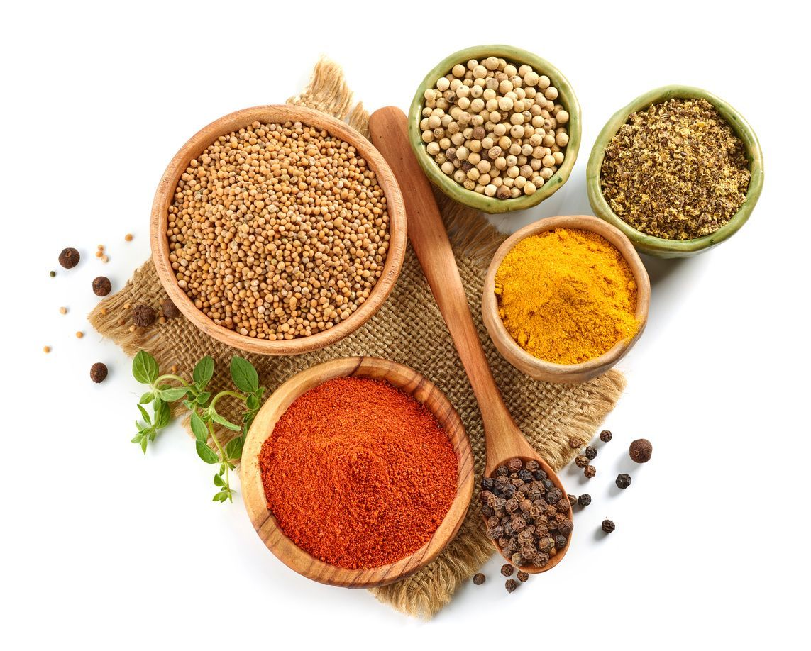 There are many different types of spices in bowls and spoons.
