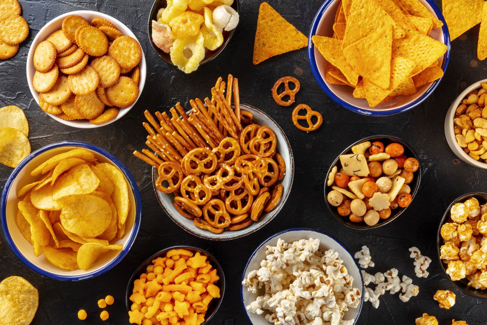 There are many different types of snacks in bowls on the table.