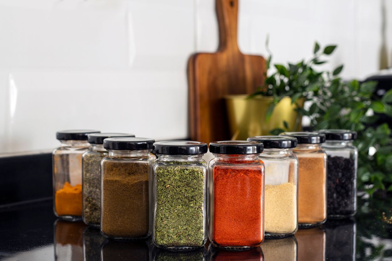 A bunch of jars of spices are sitting on a counter.