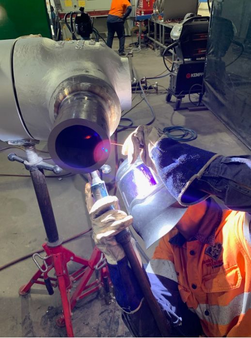 A Man Is Welding A Pipe In A Factory — Hanby Welding & Engineering In Portsmith, QLD