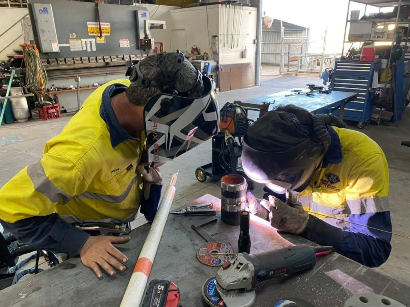 Two Men Are Welding A Piece Of Metal In A Factory — Hanby Welding & Engineering In Portsmith, QLD