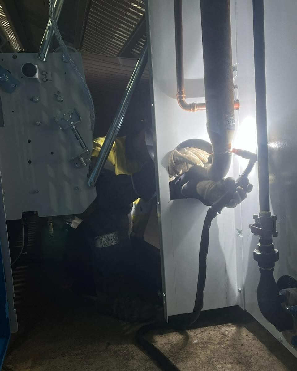 A Man Is Welding A Pipe In A Dark Room — Hanby Welding & Engineering In Portsmith, QLD