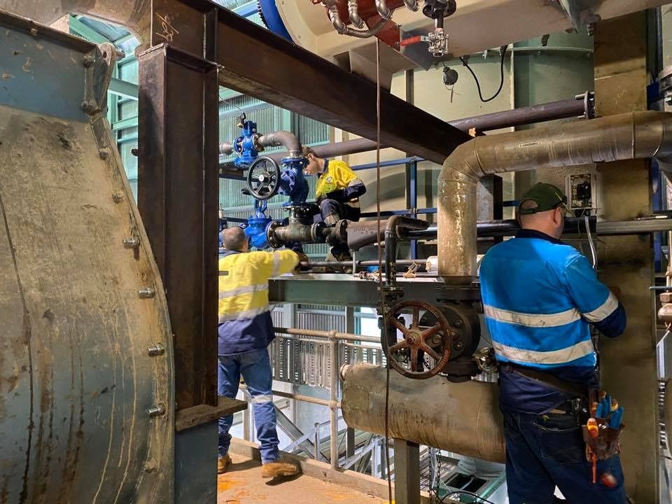A Group Of Men Are Working On Pipes In A Factory — Hanby Welding & Engineering In Portsmith, QLD