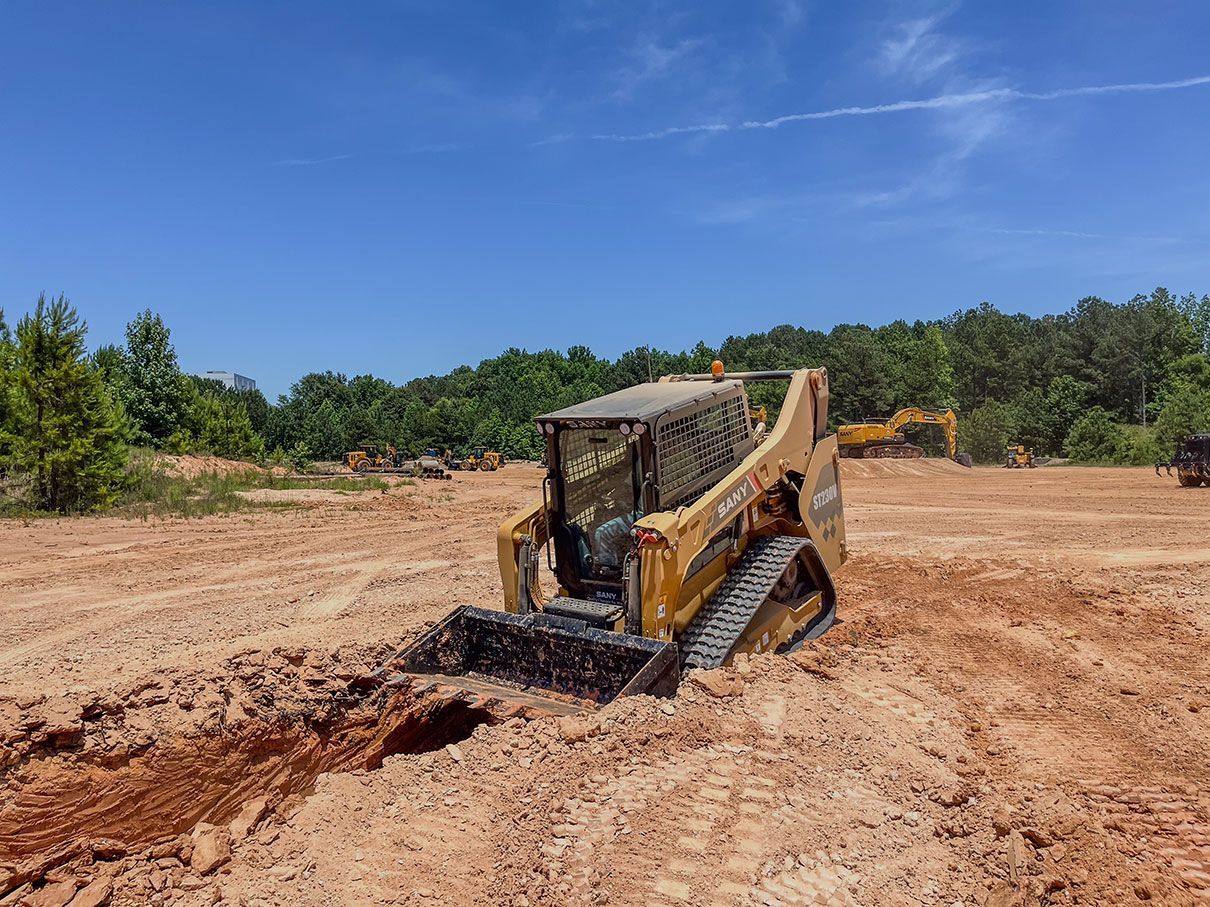 Yellow backhoe digging dirt on a construction site under a blue sky.
