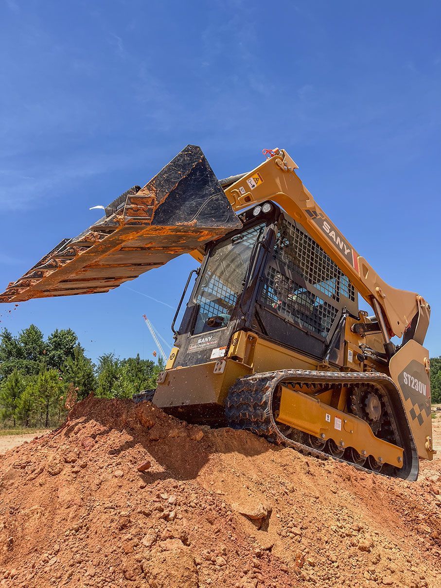 Yellow bulldozer on a construction site, moving dirt under a blue, cloudy sky.