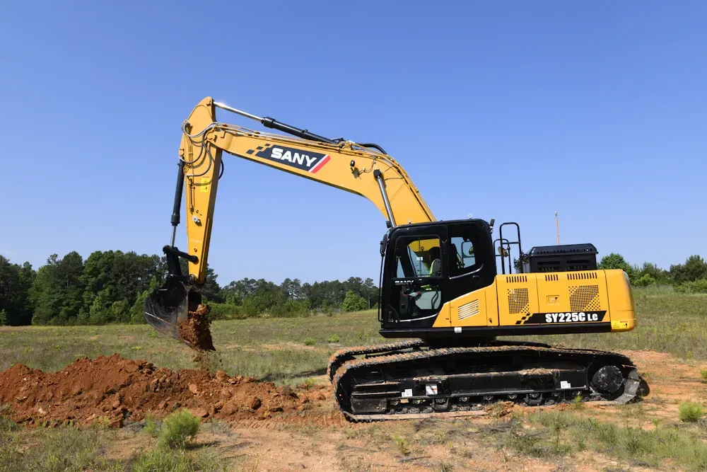 Yellow SANY excavator digging in a dirt field under a clear blue sky.