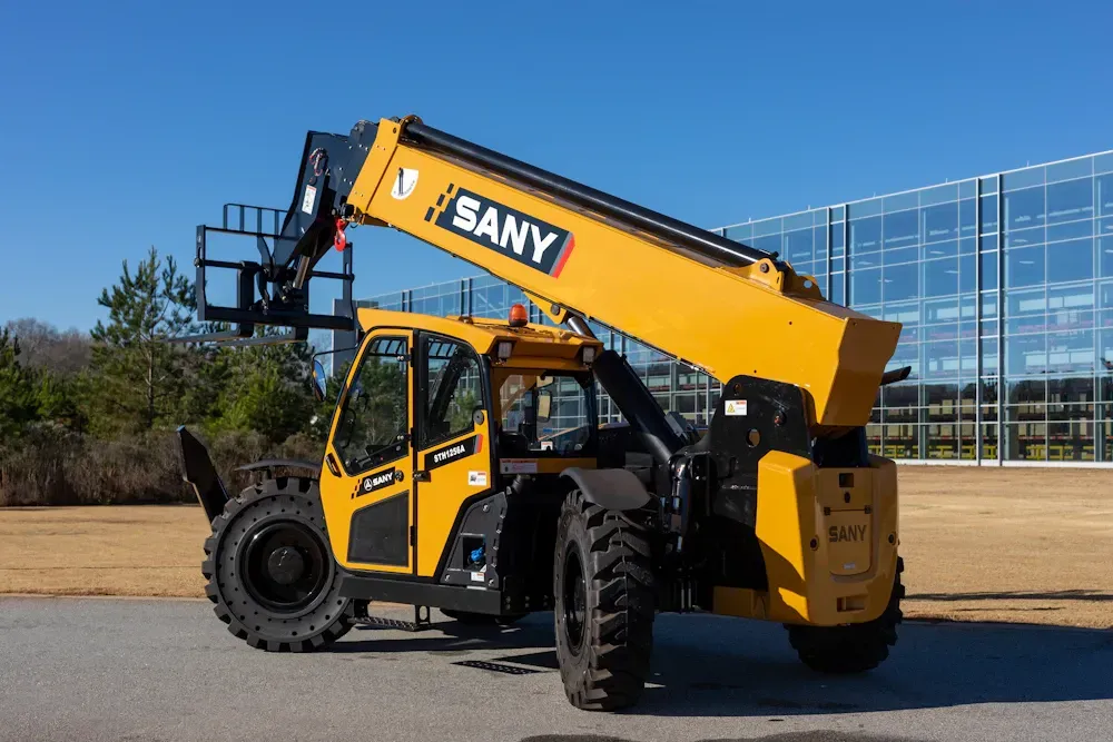 Yellow Sany telehandler with forks extended, outside on a sunny day.