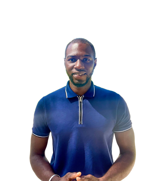 A man is sitting at a desk with a laptop and a vase of flowers.