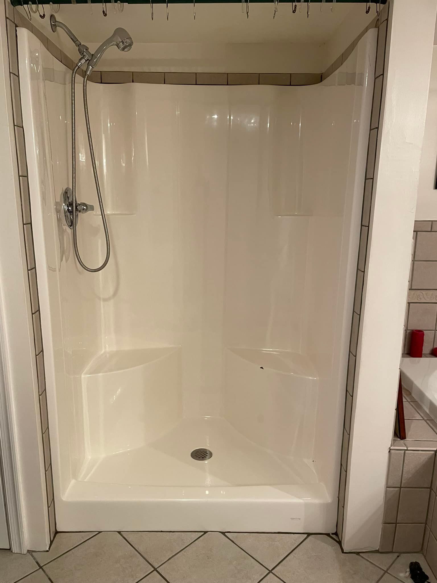 A white shower stall with a shower head in a bathroom.
