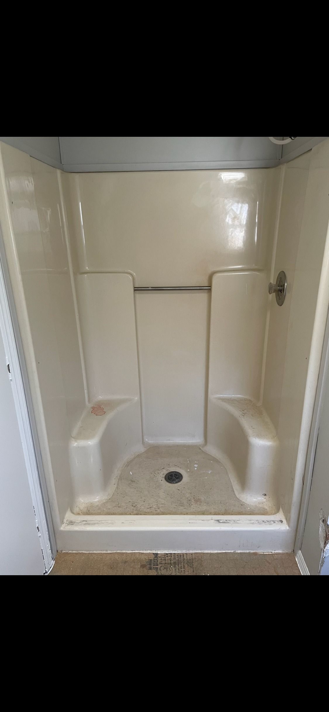 A white shower stall with two seats and a toilet.