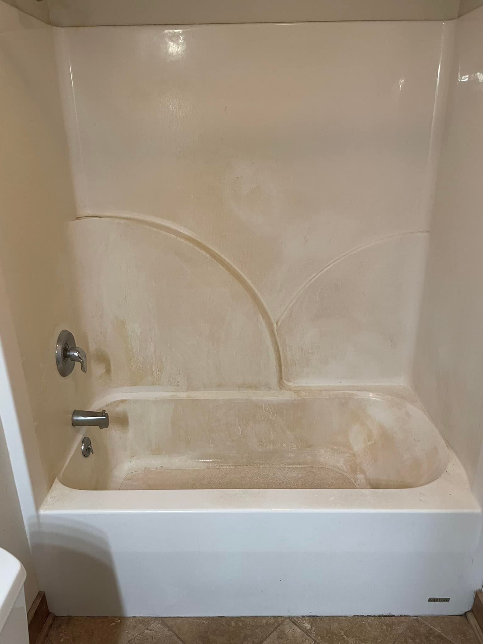 A white bathtub is sitting in a bathroom next to a toilet.