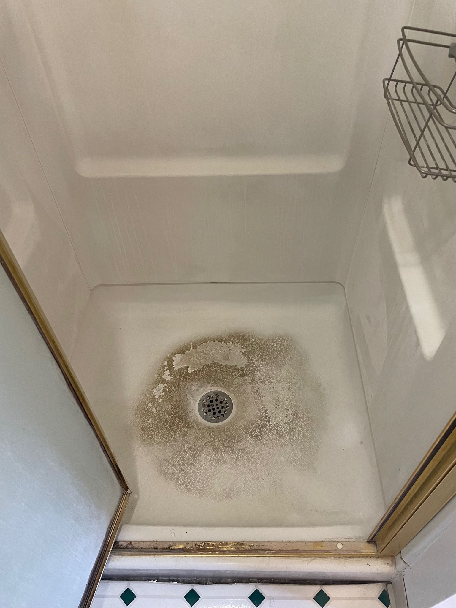 A shower stall with a drain in the middle of it.