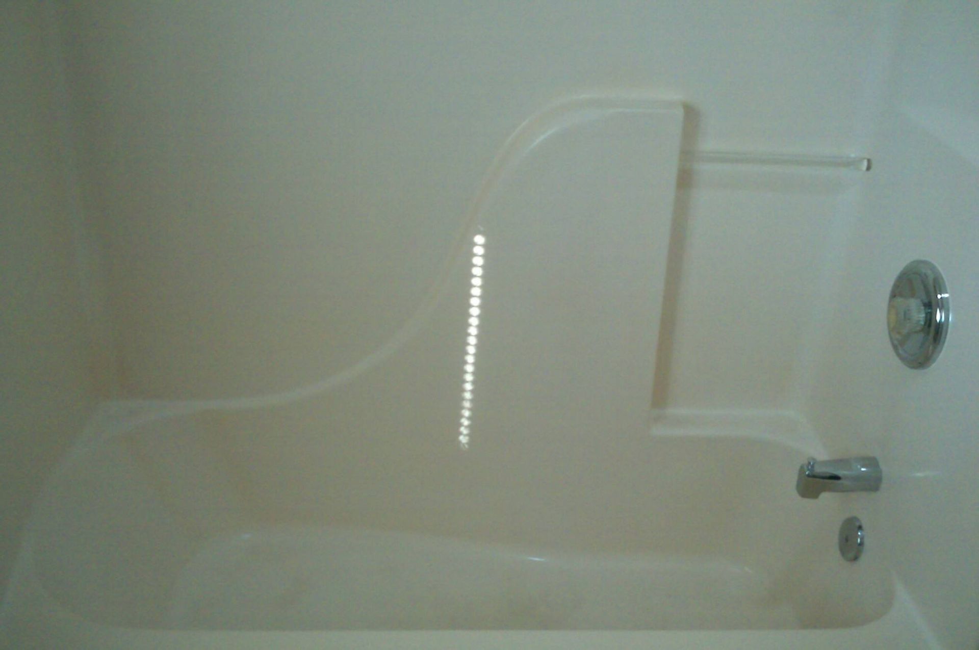A white bathtub is sitting in a bathroom next to a white wall.