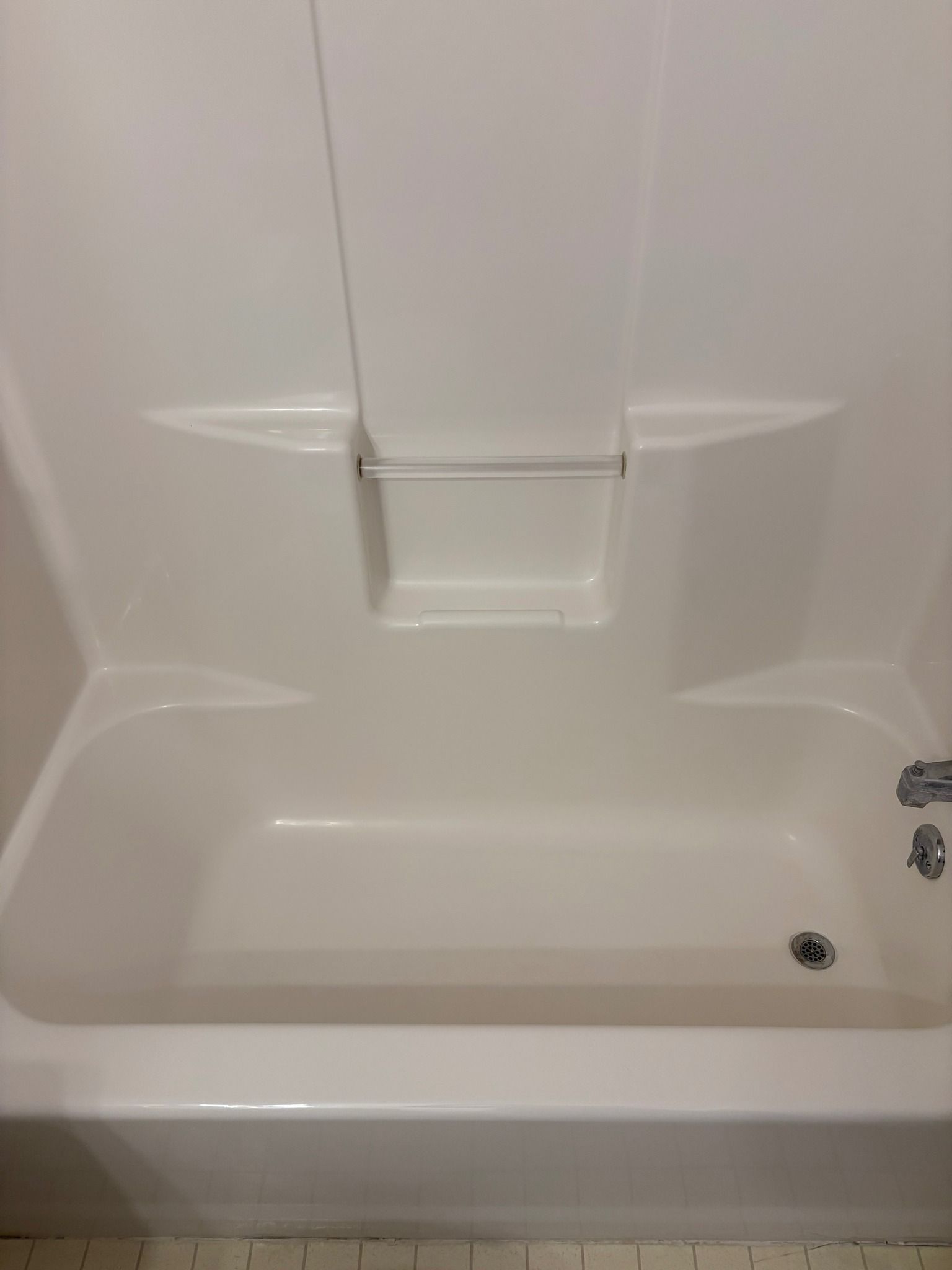 A white bathtub in a bathroom with a shower stall.