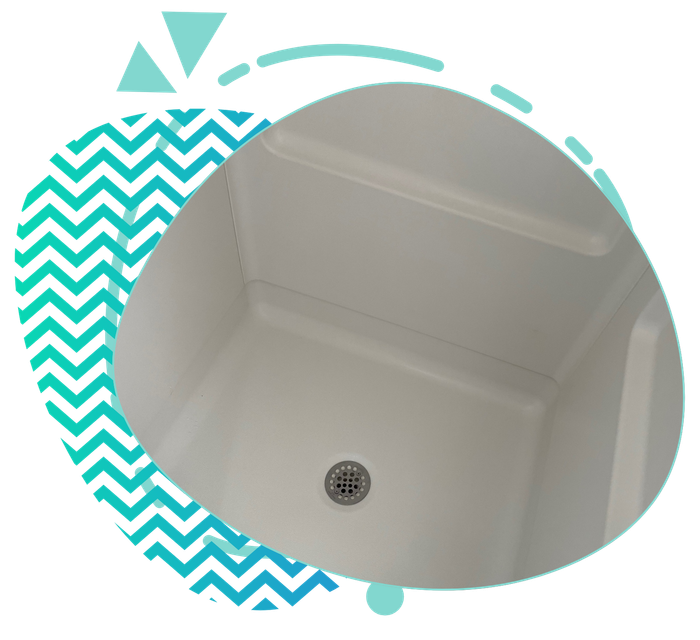 White shower base with a drain, viewed from above, within a teal and white geometric design.