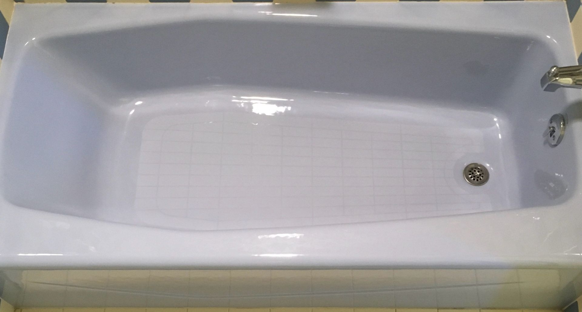 White bathtub with a textured floor and chrome fixtures.