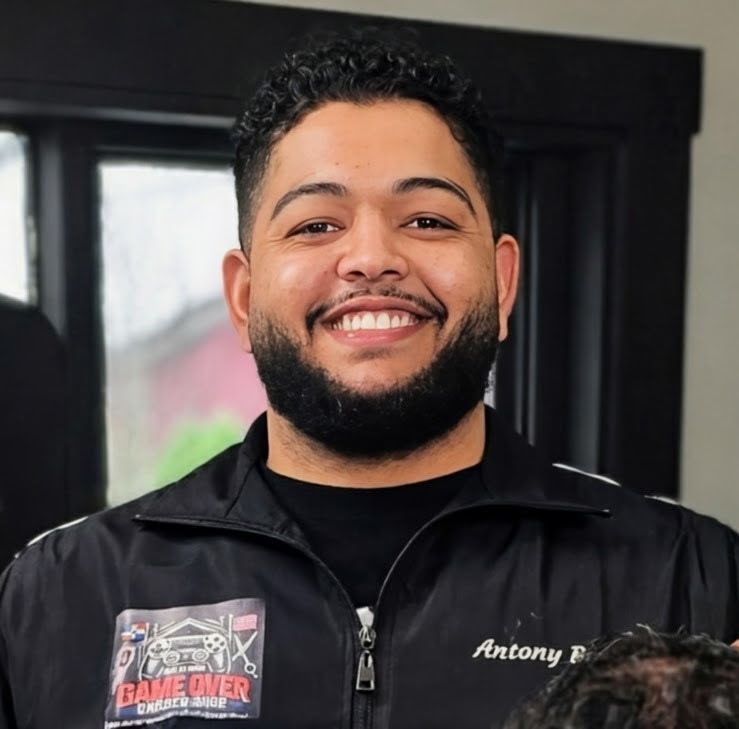 A smiling person wears a black jacket with a 