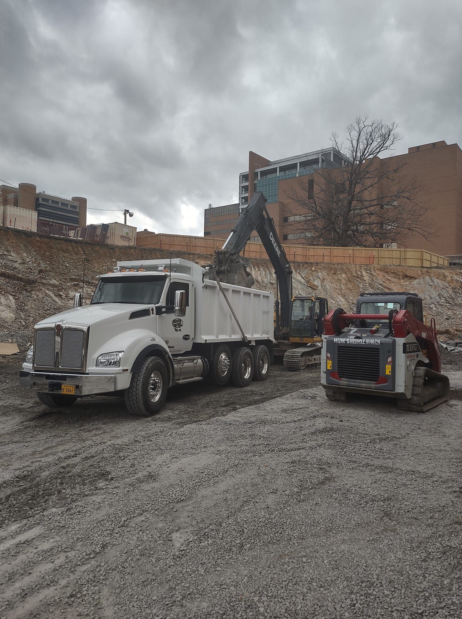 A dump truck and a bulldozer are parked in a dirt lot. A dump truck and a bulldozer are parked in a dirt lot.