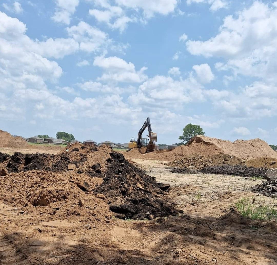 A large pile of dirt is being excavated in a field. A large pile of dirt is being excavated in a field.