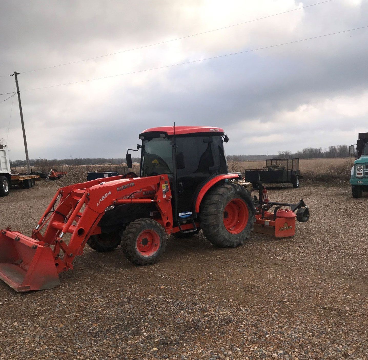 A red tractor is parked in a gravel lot.