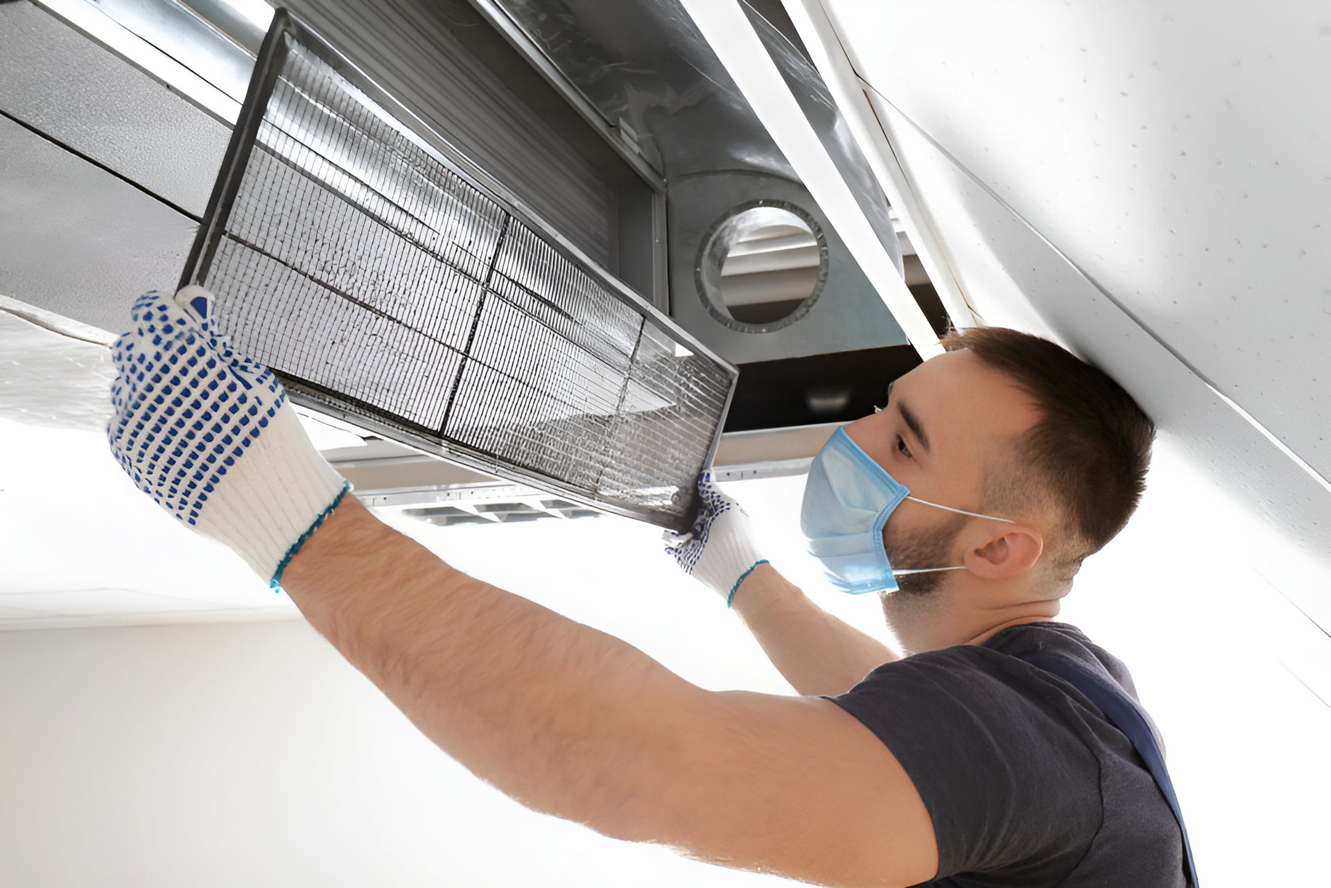 A Man Wearing A Mask And Gloves Is Cleaning An Air Conditioner — Coolmech In Gympie, QLD