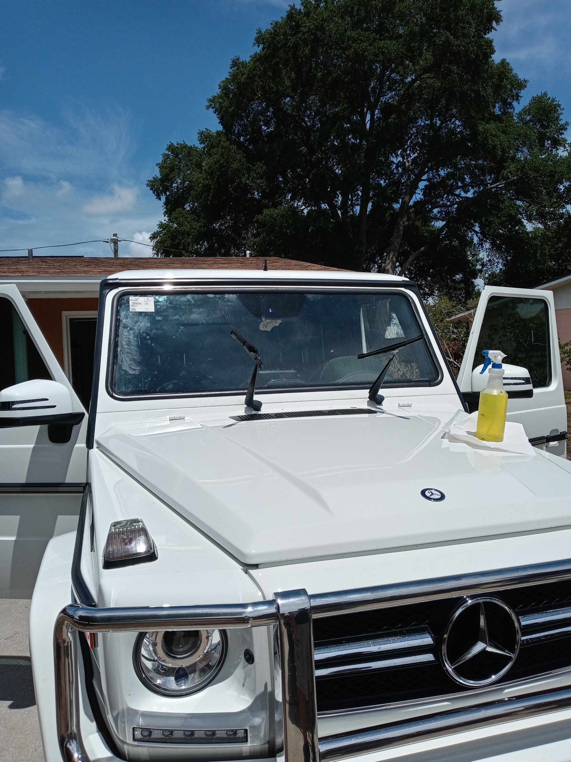 A white mercedes benz is parked in front of a house.