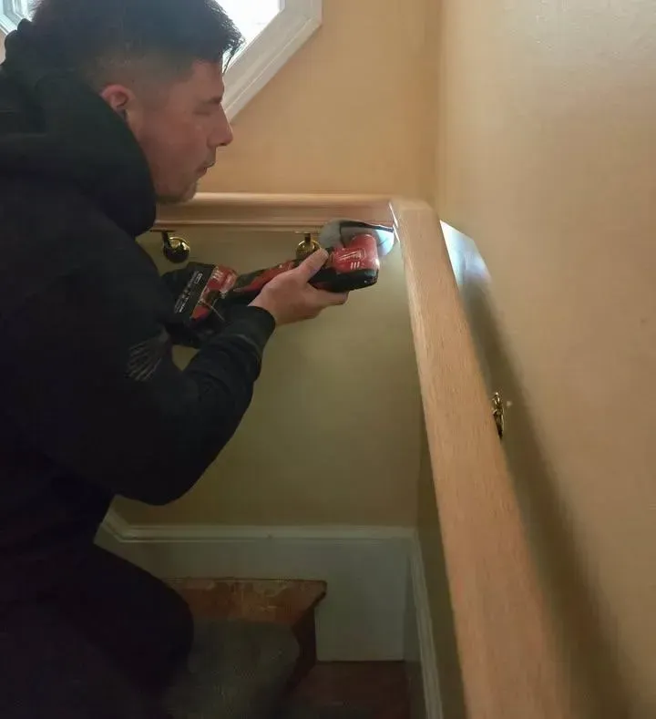 Person kneels on a staircase, using a phone to inspect a corner with a flashlight.