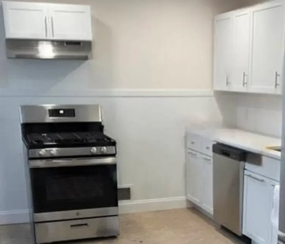 Bright white kitchen with stainless steel stove, dishwasher, and upper cabinets.