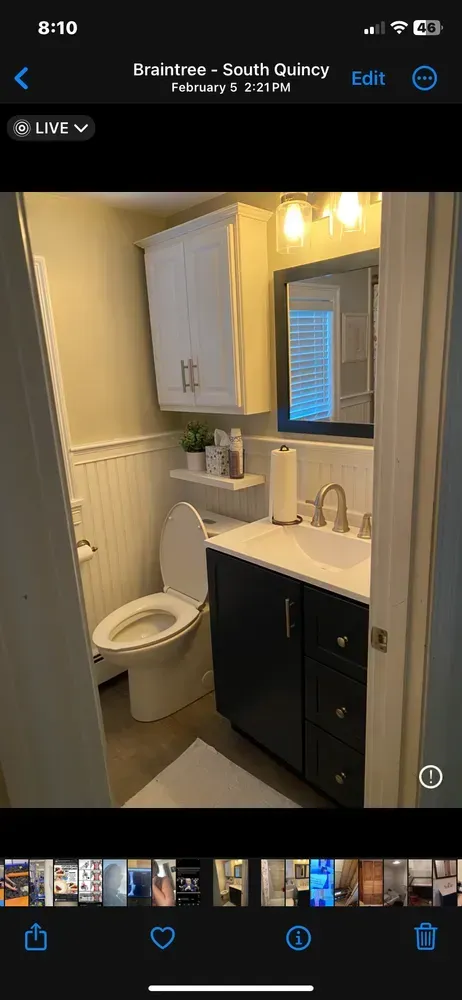Small bathroom with white sink, mirror cabinet, toilet, and dark vanity beside a shower curtain.