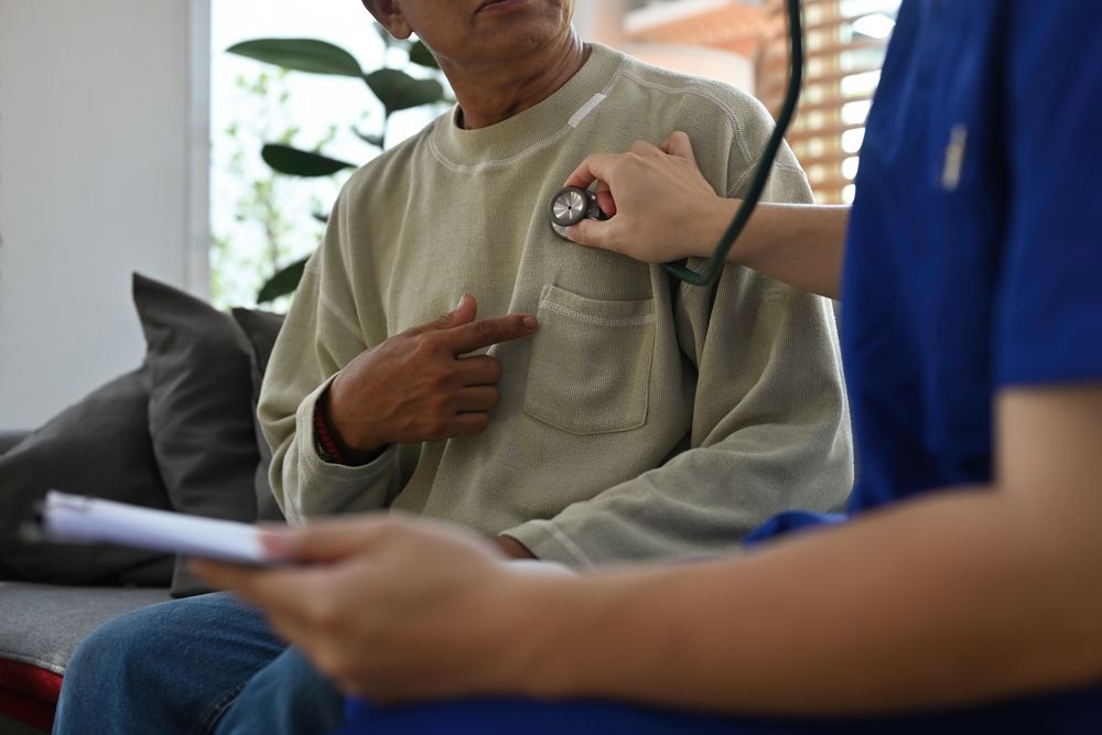 Patient being examined by a healthcare worker with a stethoscope; indoors.