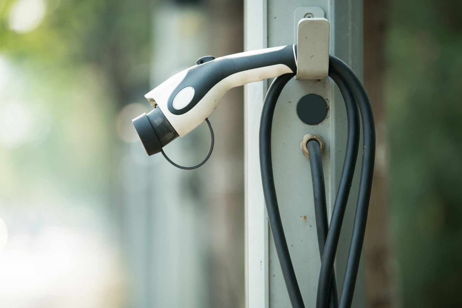 A close up of an electric car charging station on a pole.