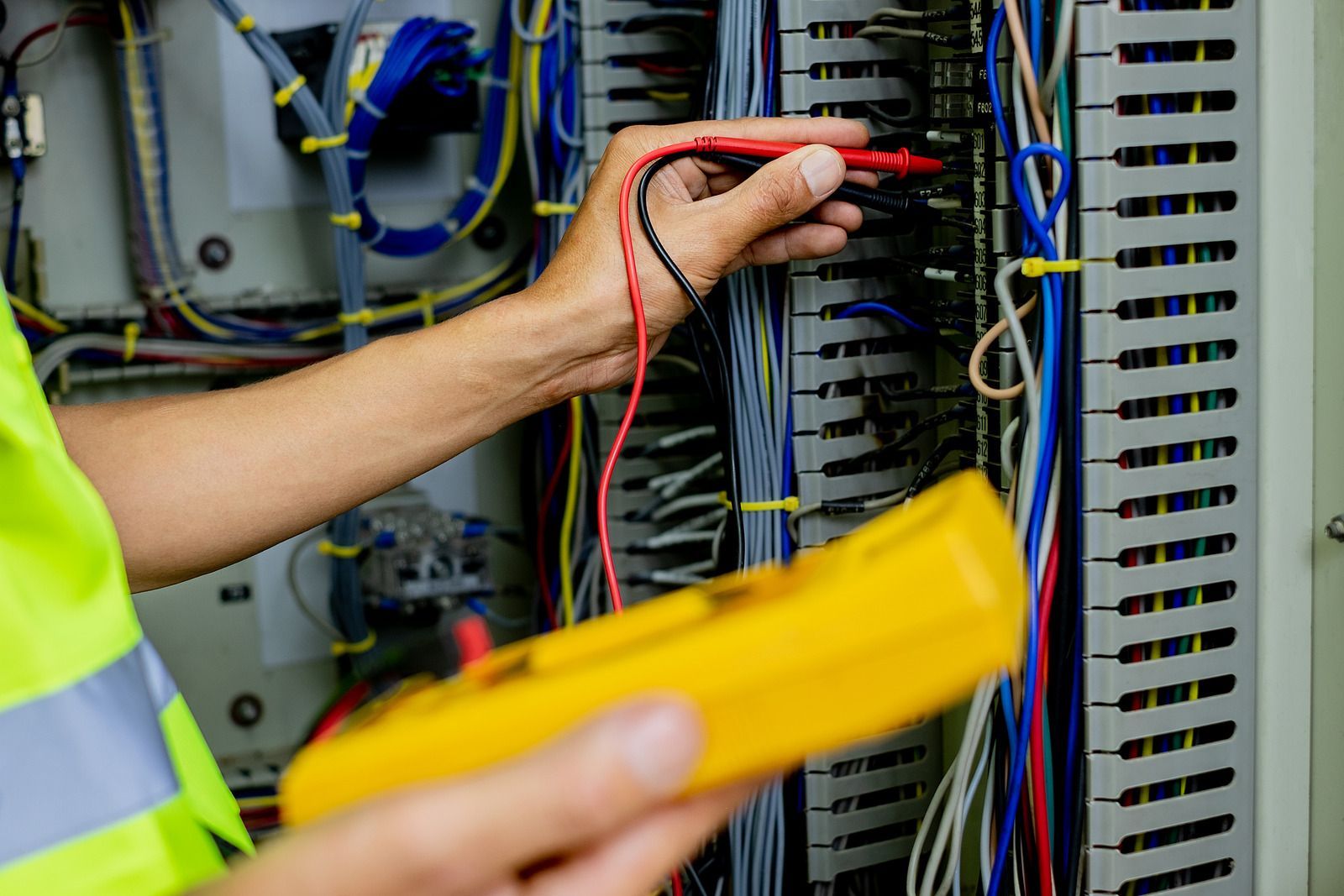 An electrician is using a multimeter to test a circuit board.