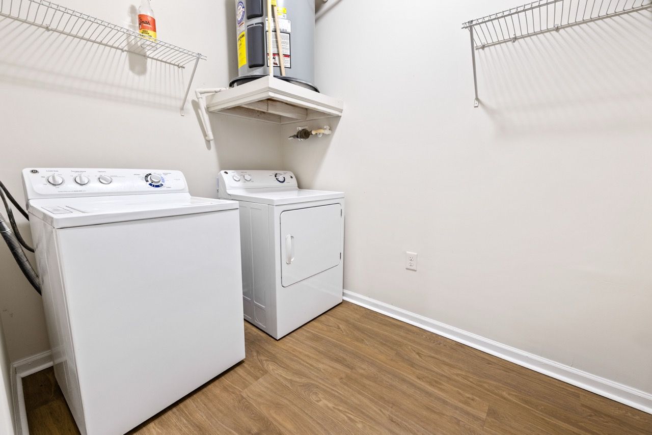 White washer and dryer in a small laundry room with wood-like flooring