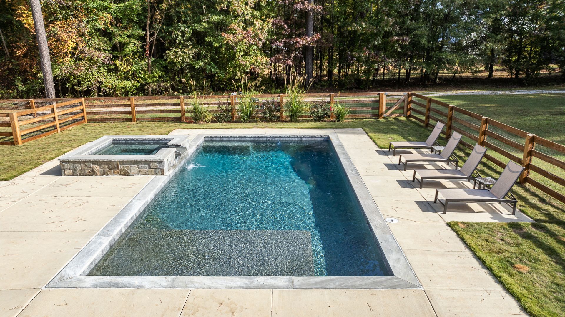 A large swimming pool surrounded by chairs and a wooden fence.