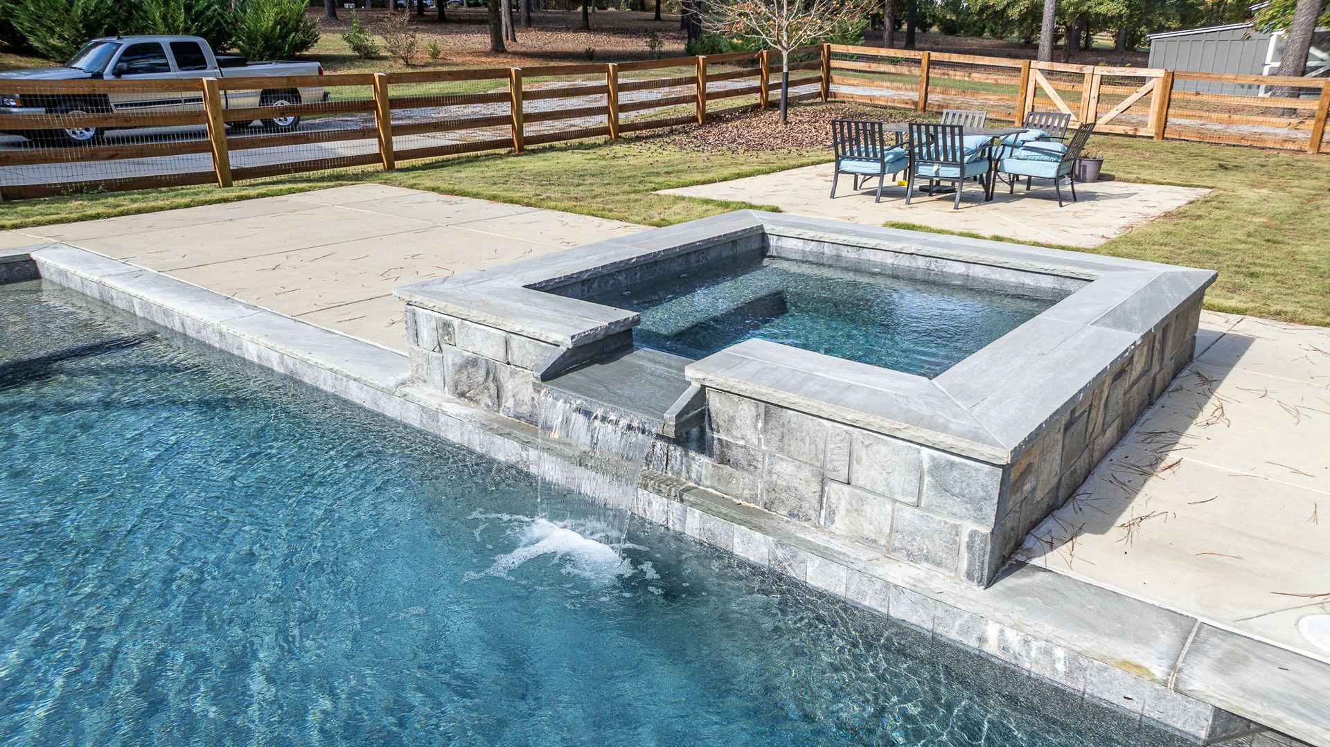 A large swimming pool with a hot tub in the middle of it.