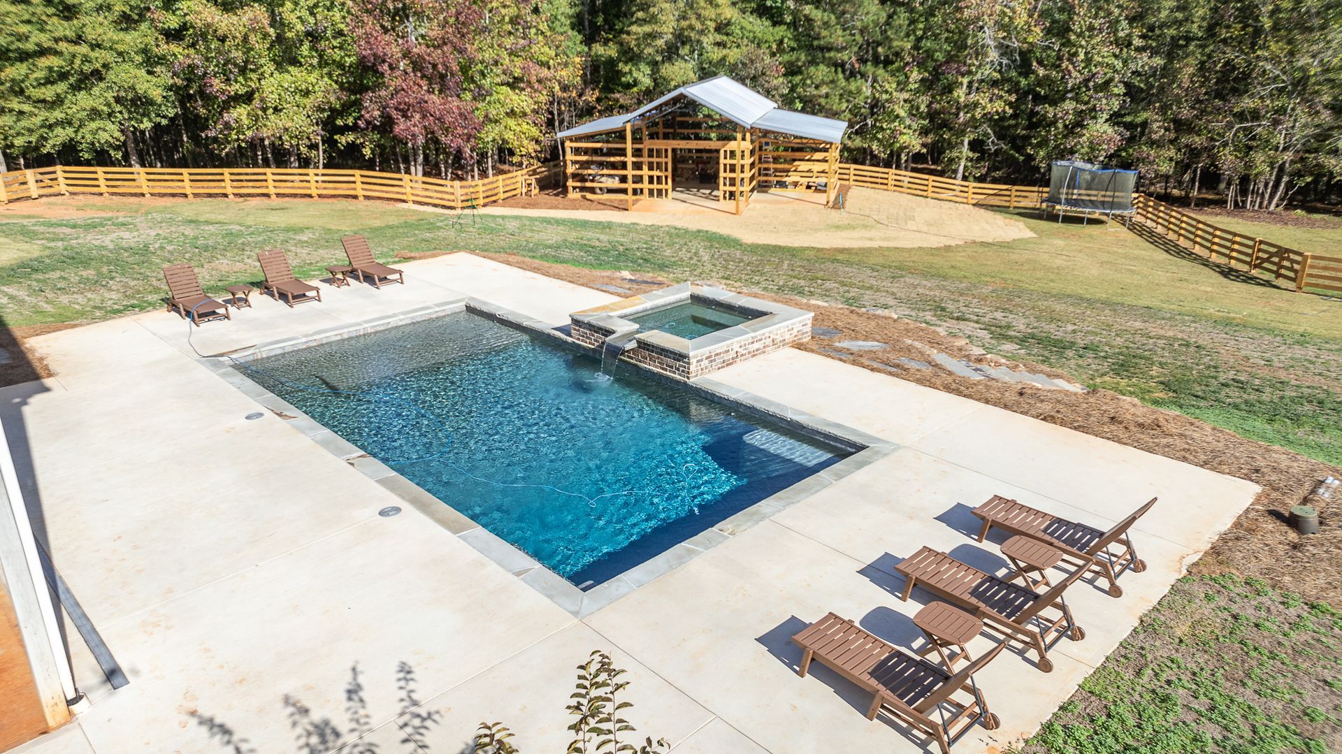 There is a large swimming pool in the middle of a lush green field.