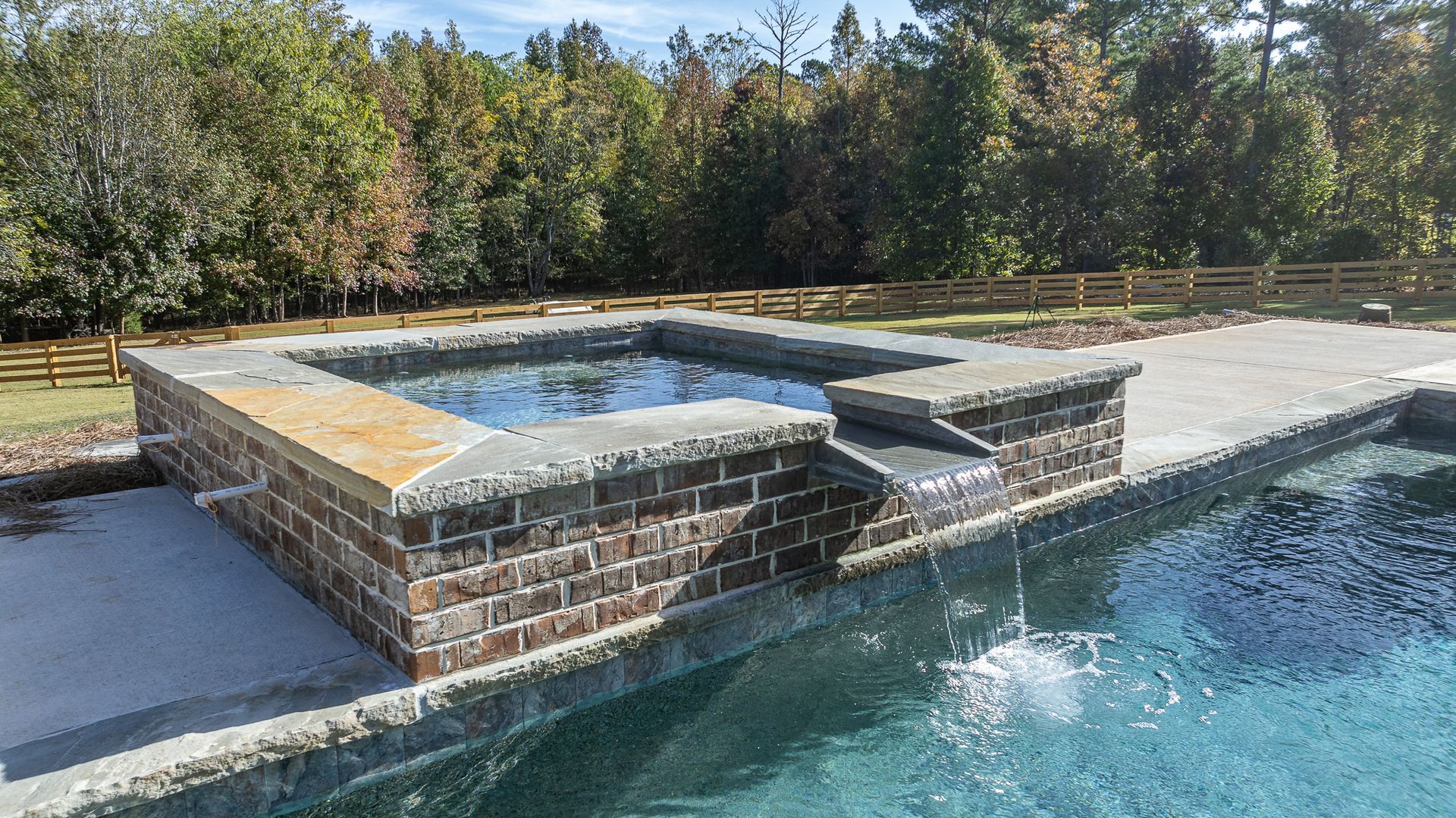 A large swimming pool with a hot tub in the middle of it.