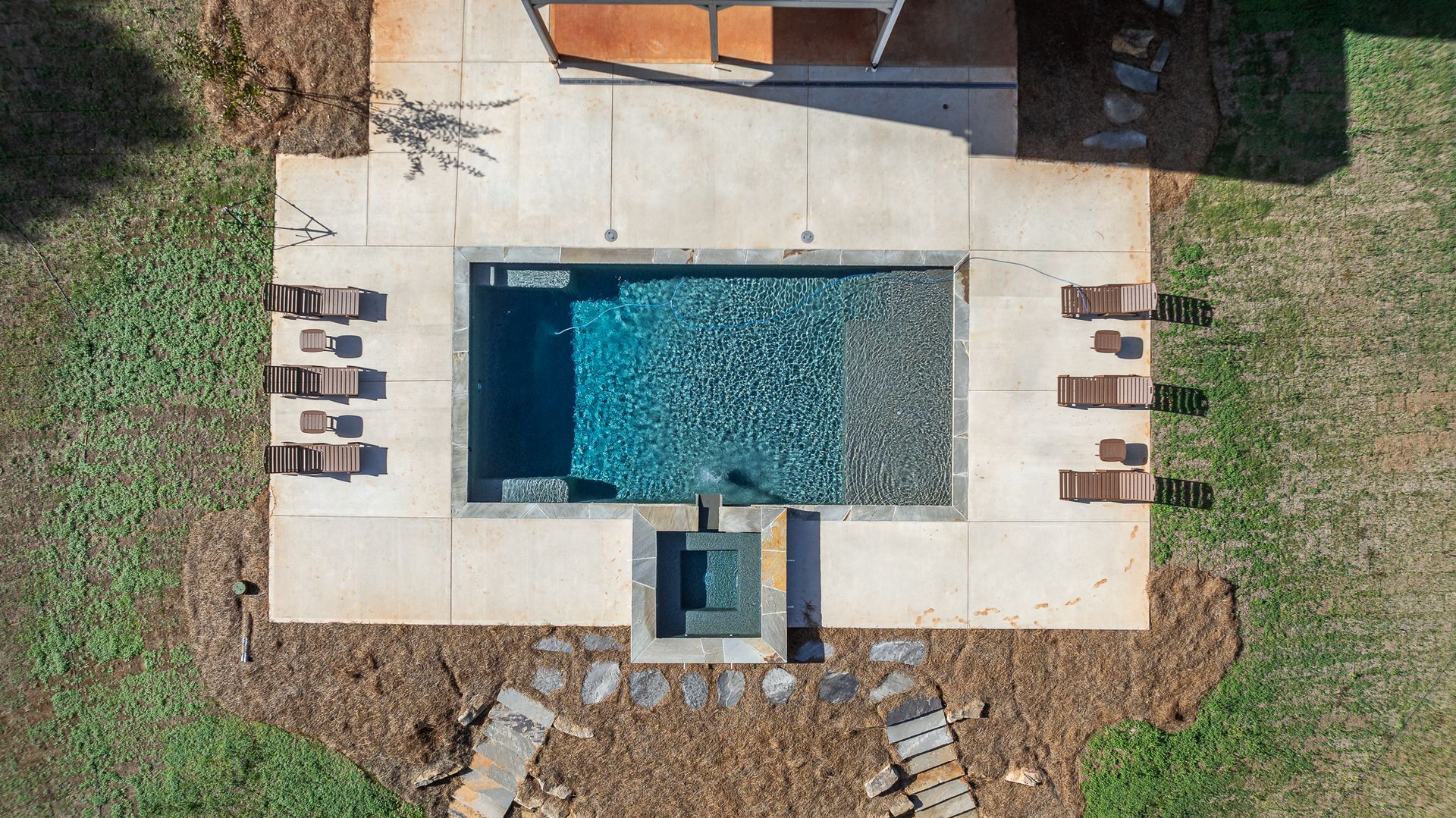An aerial view of a swimming pool in the backyard of a house.