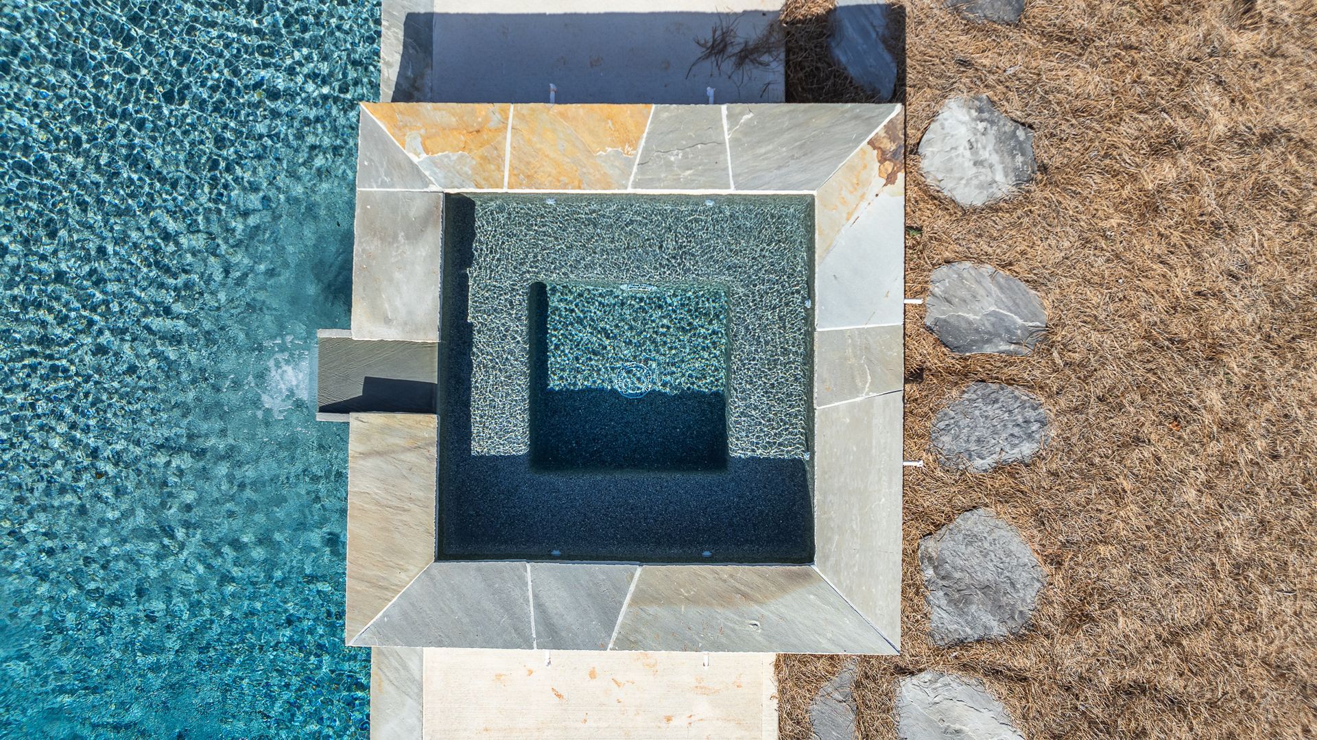 An aerial view of a swimming pool with a stone walkway leading to it.